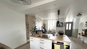 Una cucina moderna con isola centrale, forno integrato e parete decorata con pietra.