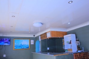 A hotel reception area with a TV, framed artwork, a counter, and a decorative shelf. - inspan lodge  (Cape Town)