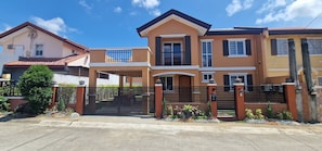 A two-story house with a gated entrance, a balcony on the upper floor, and a small porch. - Nicholas Residence (Silang)