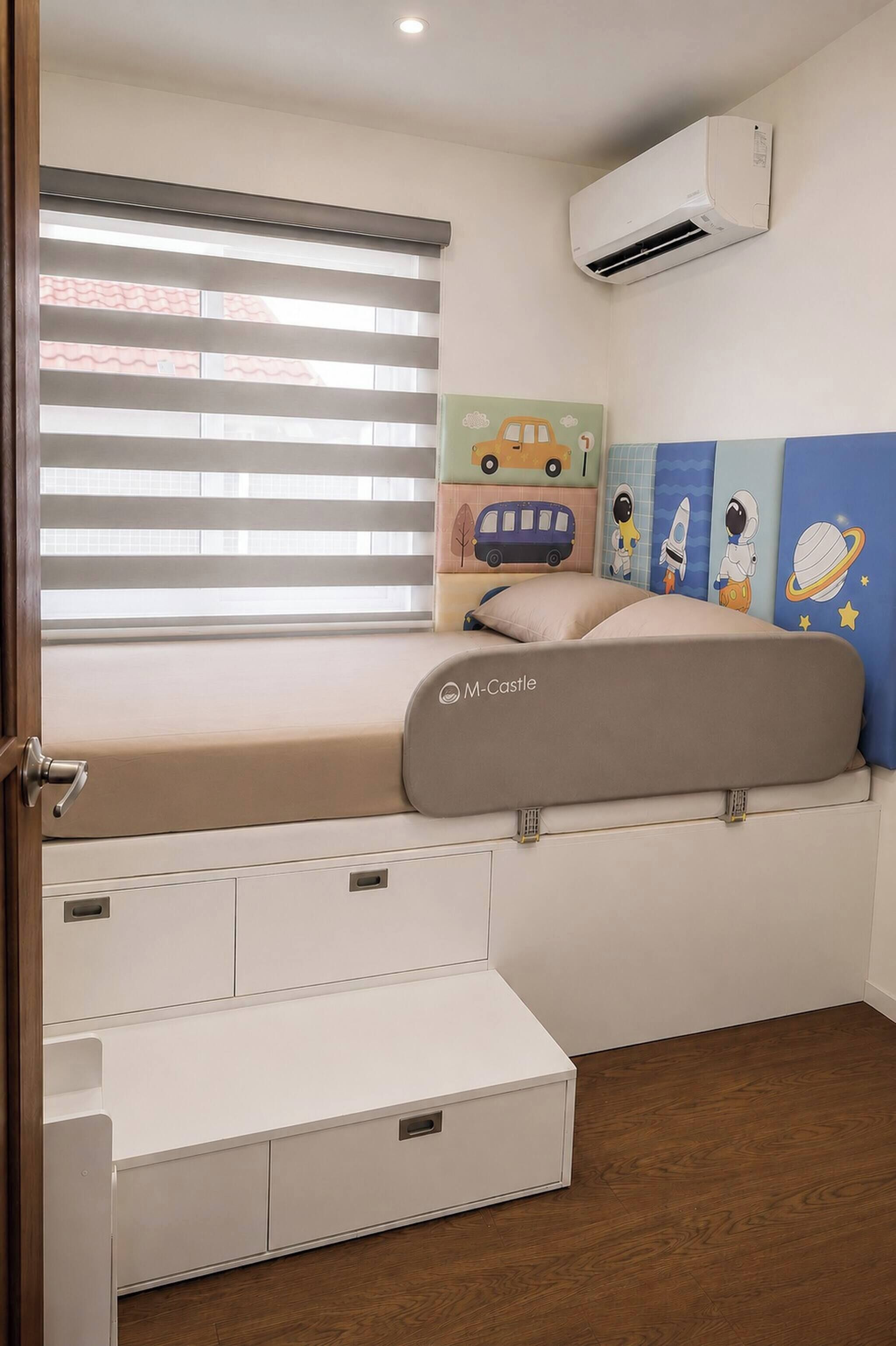 Een slaapkamer met een bed, een raam met zonwering, een airconditioner, een muur met kunstwerken over het thema ruimte, en een opbergmeubel.