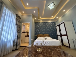Un dormitorio con cama, mesita de noche, candelabro y ventana con cortinas.