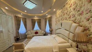 Um quarto espaçoso com uma cama grande, um espaço para sentar e um guarda-roupa.