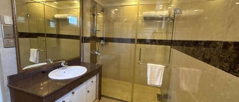 Un baño moderno con ducha de vidrio, un lavabo con encimera de mármol y una bañera.