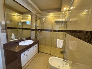 Un baño moderno con ducha de vidrio, un lavabo con encimera de mármol y una bañera.