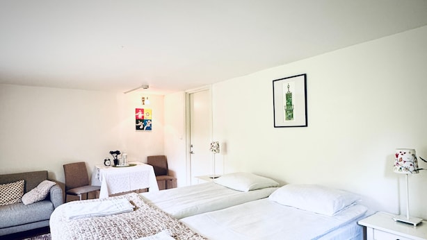 Ein Zimmer mit zwei Betten, einem Schlafsofa, einem kleinen Tisch und einer Lampe.