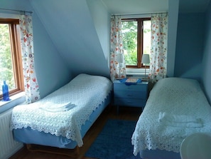 Un dormitorio con dos camas individuales, un escritorio pequeño, una ventana con cortinas y un radiador.