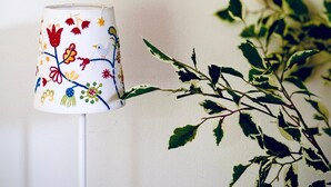 Eine Lampe mit floralem Dekor auf einem weißen Standfuß.