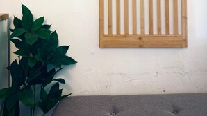Ein Wandpaneel aus Holzleisten, ein Blumentopf und ein graues Sofa.