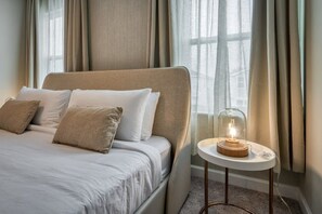 A bed with a headboard, a bedside table with a lamp, and a window with curtains. - 5BR Disney villa • Pool • Themed rooms (Kissimmee)
