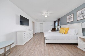 Ein Schlafzimmer mit Bett, Fernseher, Deckenventilator und Schreibtisch.