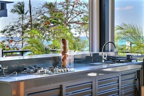 A kitchen with a stainless steel countertop, a sink, and a view of the ocean through large windows. - Cozy 1-bedroom apartment jacuzzi Las Terrenas with AC (Las Terrenas)