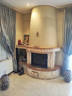 A living room with a fireplace, a radiator, and a decorative wall piece.