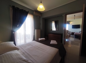 A hotel room with a bed, a dresser, a mirror, a television, and a bathroom visible through an open door.