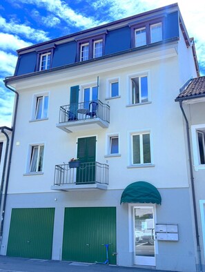 A multi-story residential building with balconies, green shutters, and a garage door. - SwissHut Modern 5min Interlaken West Station (Interlaken)
