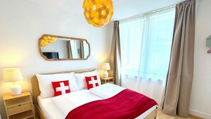 Ein Hotelzimmer mit einem Bett, einem Nachttisch, einer Lampe, einem Spiegel und einem Fenster mit Vorhängen.