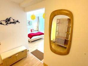 Une chambre à coucher avec un lit, une table de chevet, un miroir et une vue sur une autre pièce.