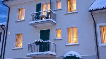 A multi-story building with a balcony, windows, and a door.