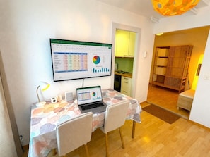 Une pièce comprenant un bureau, un ordinateur portable et un grand écran affichant un tableau de données budgétaires.