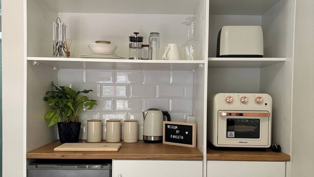 Une cuisine compacte équipée d’un réfrigérateur DEFY, d’un four à micro-ondes et d’une machine à café posés sur le plan de travail.