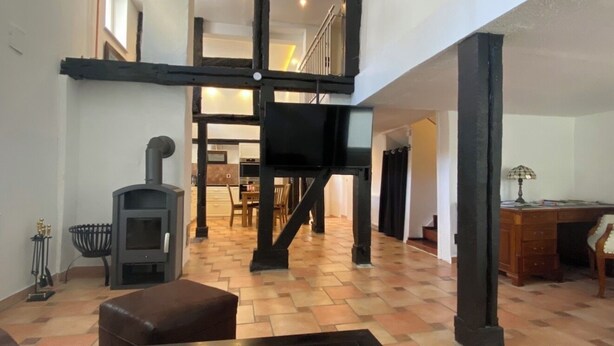 Amplia sala de estar con chimenea, una escalera y un comedor.