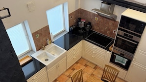 Cocina compacta con fregadero, estufa y comedor, que presenta un salpicadero de azulejos y una ventana.