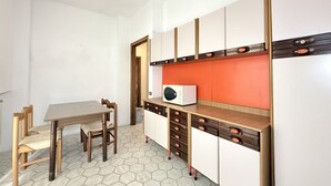 A compact kitchen with a microwave, wooden cabinets, and a hexagonal tiled floor. - SE267 – Senigallia, two-bedroom apartment 300 metres from the sea (Senigallia)