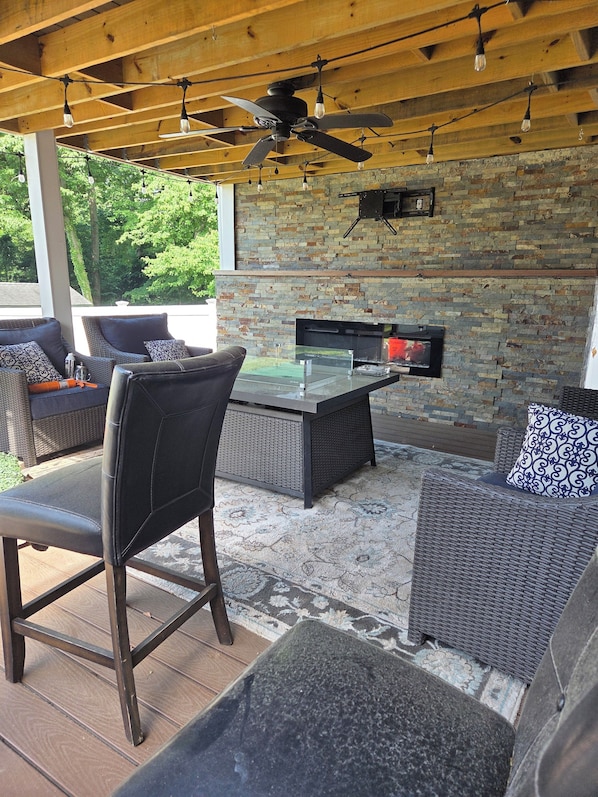 An outdoor patio with wicker furniture, a ceiling fan, and a stone wall.