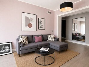 A modern living room with a grey sectional sofa, a round coffee table, and framed artwork on the wall. - Cozy, newly renovated apartment in Alassio with private garage (alassio)