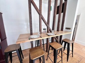 Ein Essbereich mit einem Holztisch, vier Hocker und einer weißen Wand.
