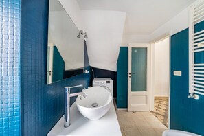 Ein modernes Badezimmer mit einem weißen Waschbecken, einem Spiegel und einer Dusche.