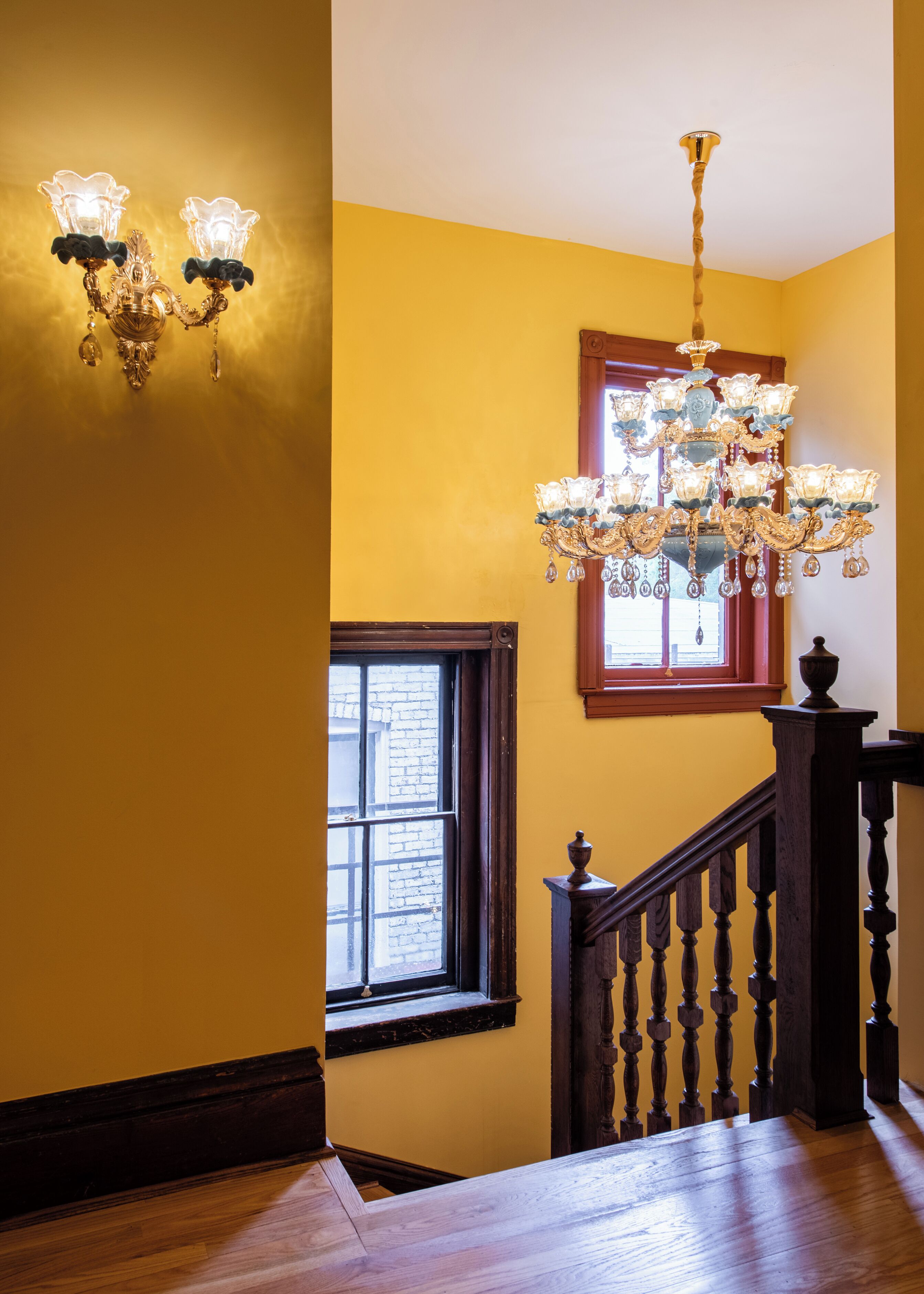 A staircase with a wooden handrail and a chandelier.