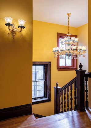 A staircase with a wooden handrail and a chandelier.