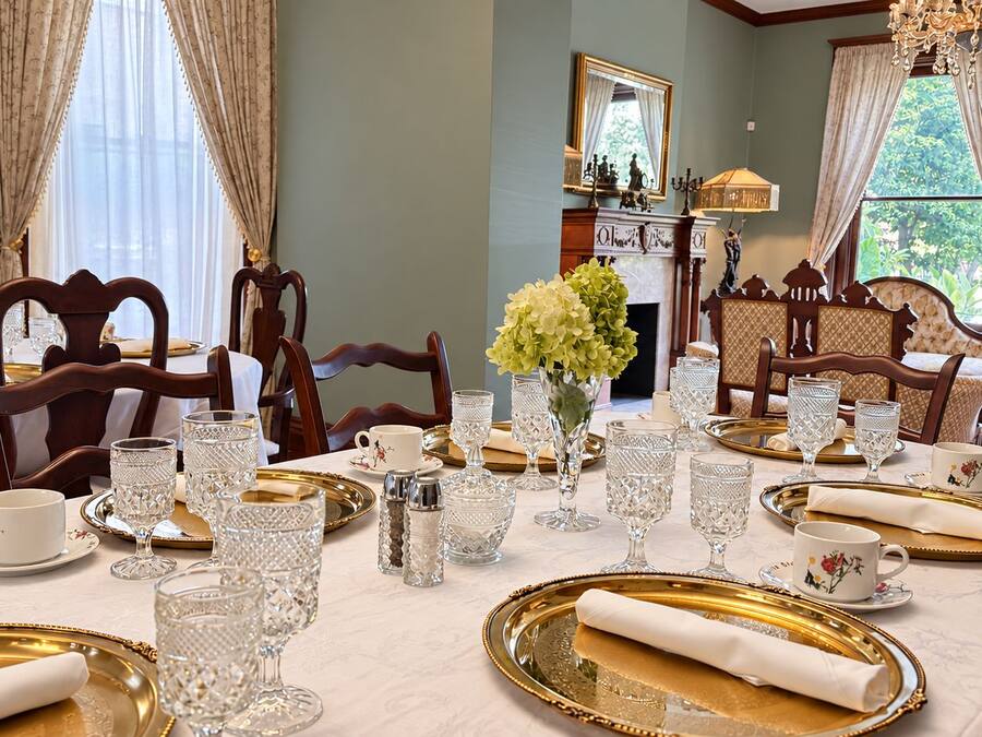 Een elegant eetzaal met een gedekte tafel, inclusief drinkglazen, borden en een vaas met bloemen.