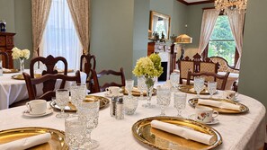 Un comedor elegante con una mesa dispuesta para una comida, incluyendo cristalería, platos y un florero con flores.