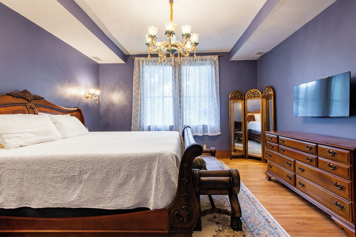 Une chambre à coucher avec un lit, une commode, un miroir et un lustre.