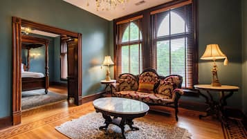 A room with a bed, a sofa, a table, and a chandelier.