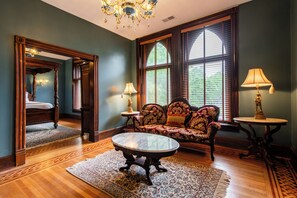 A room with a bed, a sofa, a table, and a chandelier.