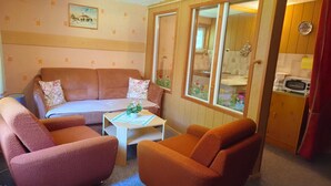 A cozy room with a sofa, two armchairs, a small table, and a window with a view of the outside. - Cozy vacation home in the countryside (Prenzlau)