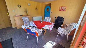 A room with a dining table, chairs, a small cabinet, a radiator, and a door. - Cozy vacation home in the countryside (Prenzlau)