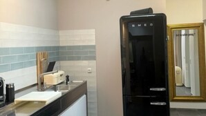 A kitchen with a black refrigerator, a clock, and a wall-mounted deer head decoration. - Beautiful city apartment (Würzburg)