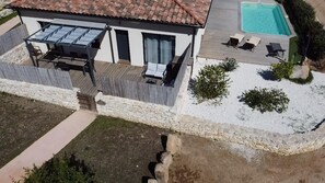 Une maison à deux étages avec une piscine, un espace salon extérieur et une terrasse clÎturée.