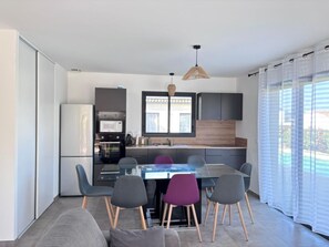 A modern kitchen with a dining area, a refrigerator, microwave, and a large window.