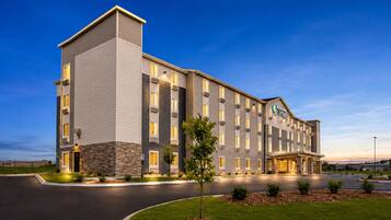 A multi-story hotel with a stone facade, a flat roof, and a well-lit entrance.