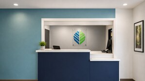 Una reception con arredamento nei toni del blu e del bianco, un logo a parete e un quadro appeso alla destra.