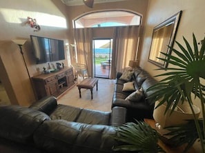 Ein Wohnzimmer mit einer Couch, Fernseher und Blick ins Freie.