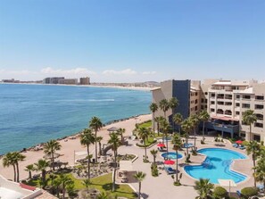 Un resort con piscina, palmeras y vista al mar.