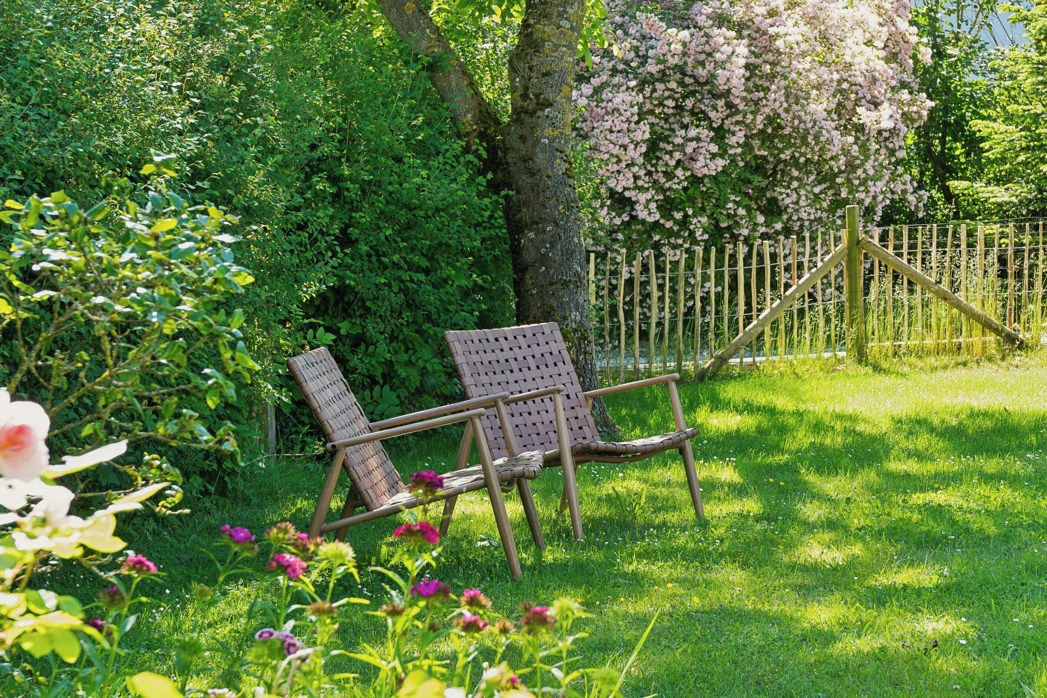 Un jardin avec un banc en bois, une végétation luxuriante et une clôture en bois.