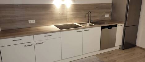 A modern kitchen with a built-in dishwasher, stainless steel appliances, and a wooden countertop.