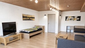 Uma sala de estar moderna com uma cama, uma TV, um sofá e uma mesa de jantar.