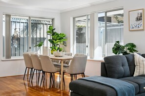 Ein modernes Wohnzimmer mit Essbereich, großen Fenstern und Blick ins Freie.